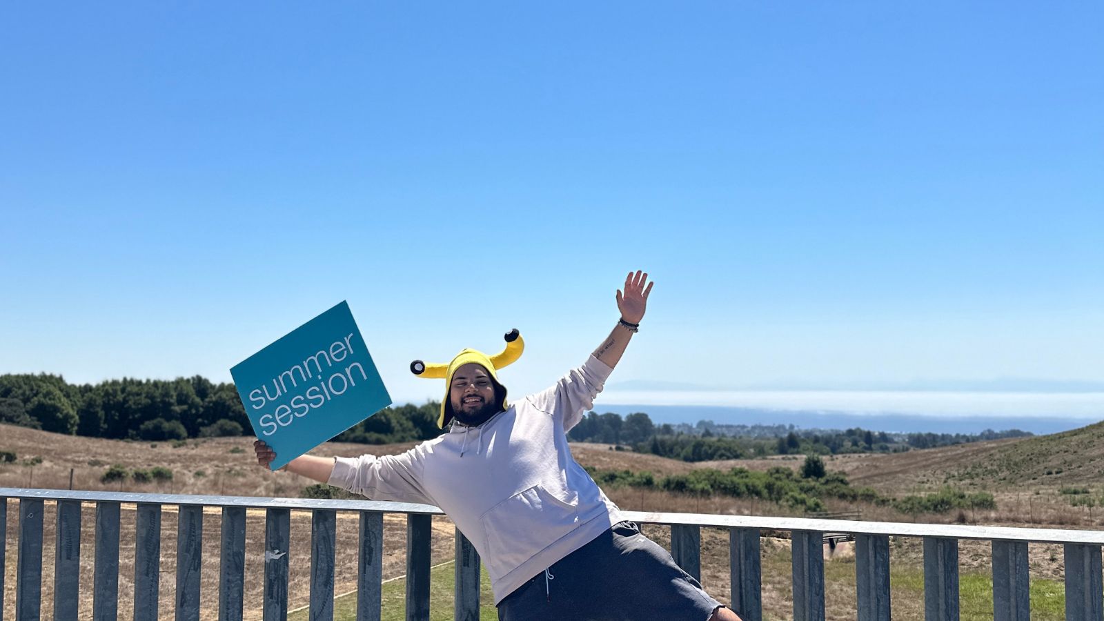Events Calendar – Enrollment Open student holding summer session sign