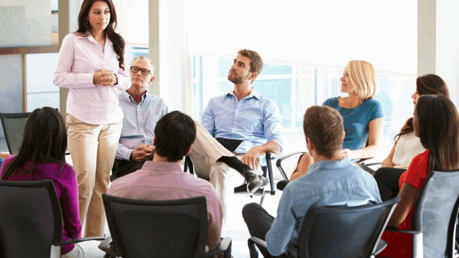 Woman presenting in front of people sitting in a circle.