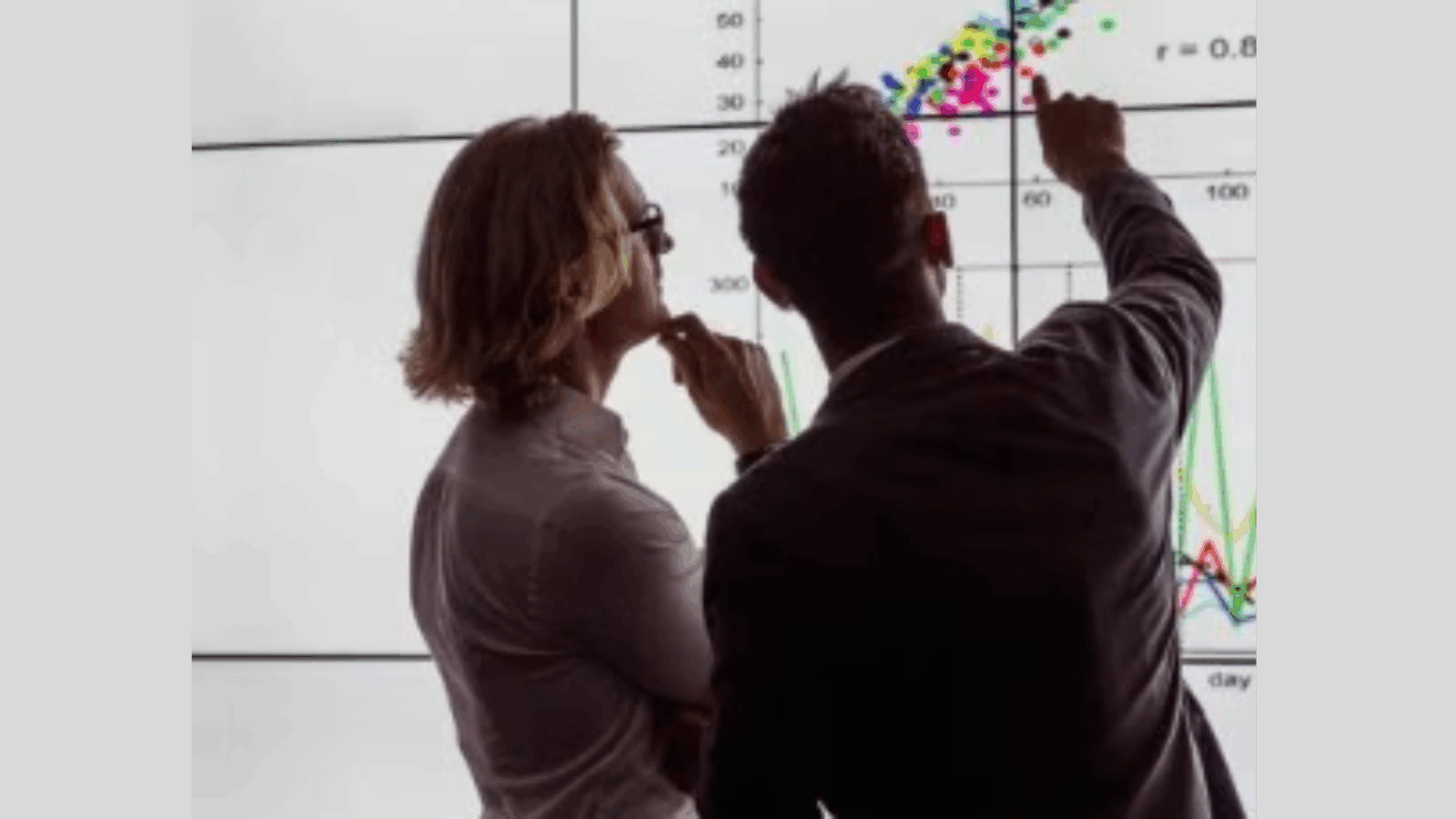 Two people looking at a chart on a whiteboard.