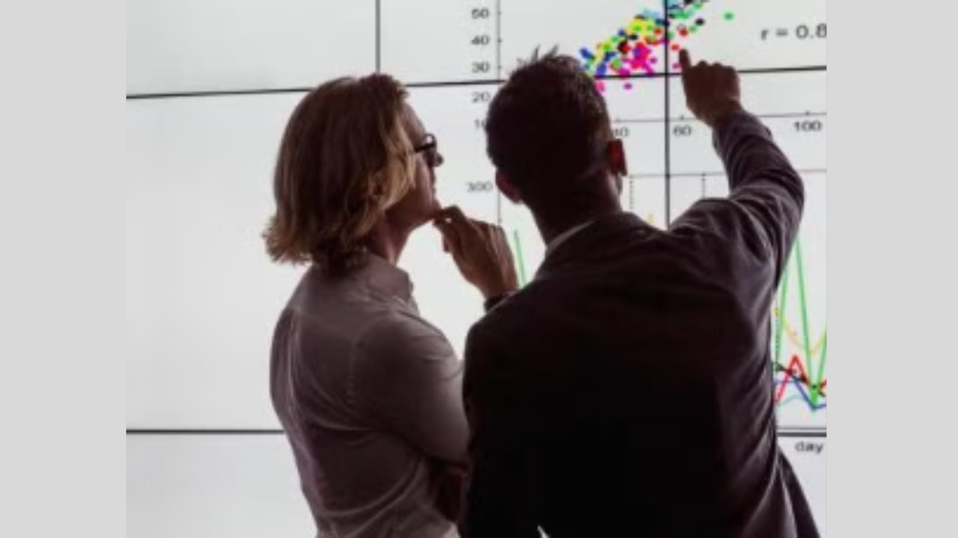 Two people looking at a chart on a whiteboard.