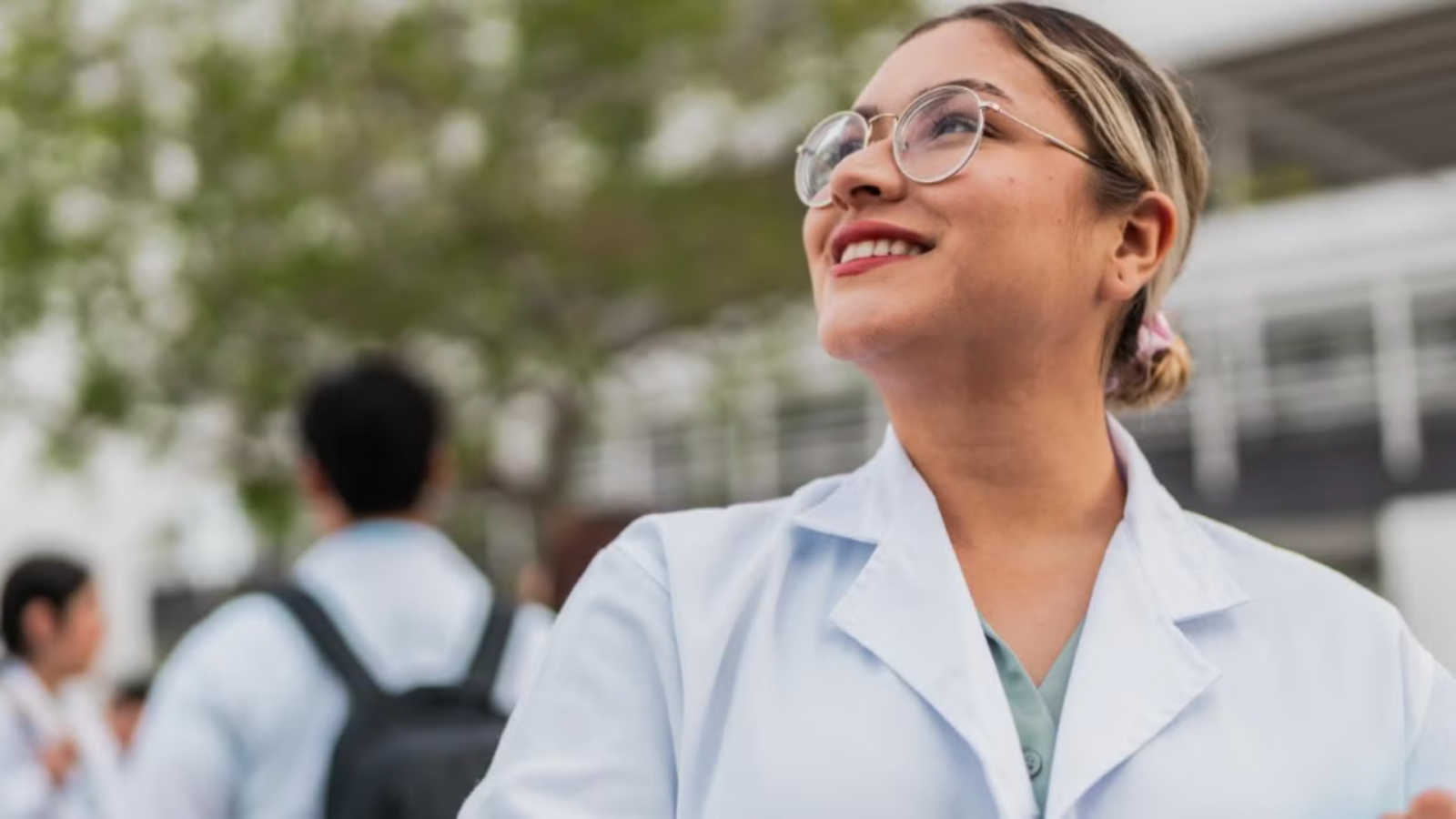 Woman standing outside wearing a lab coat.
