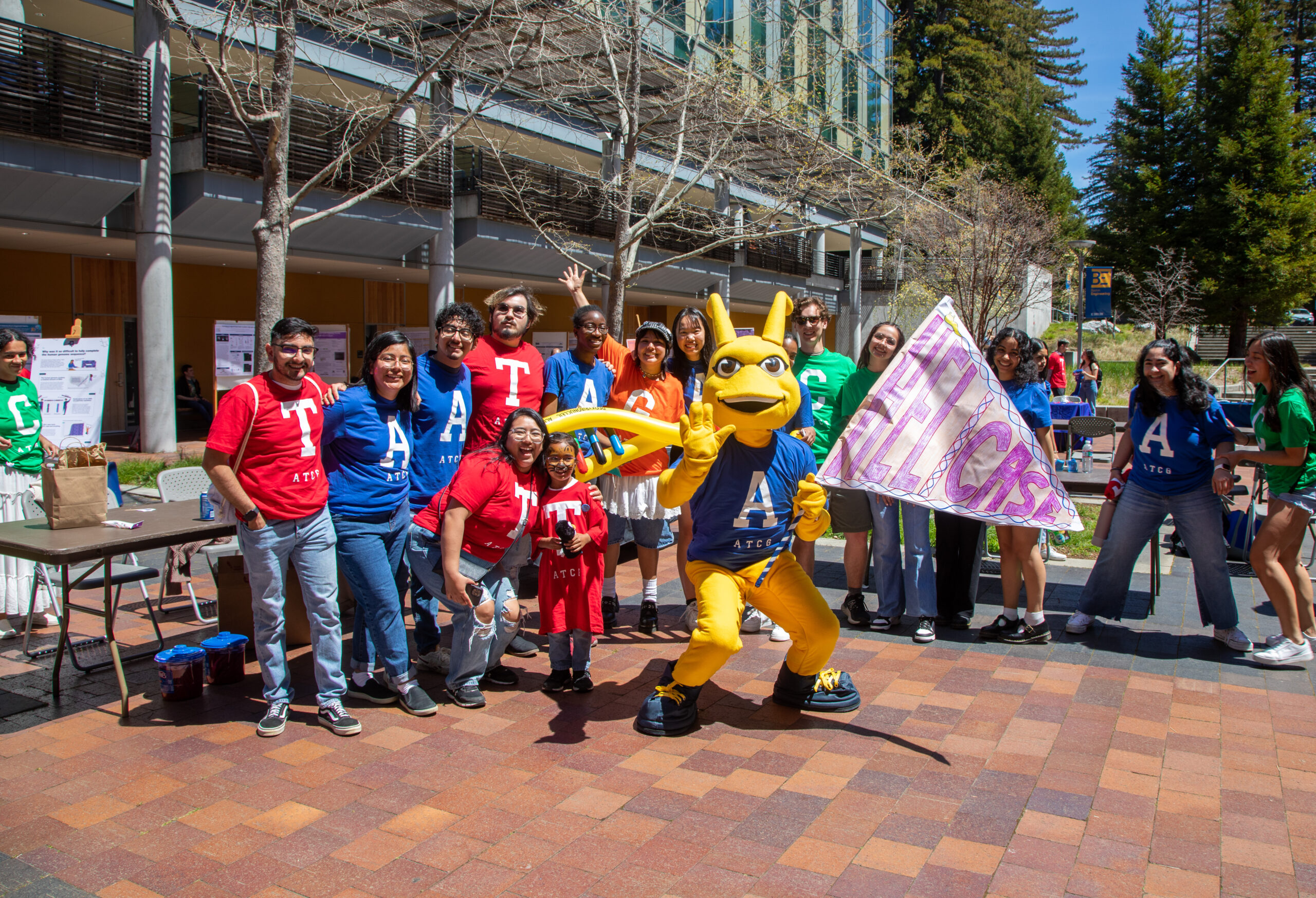 The sammy slug mascot poses with students who are wearing DNA Day shirts.