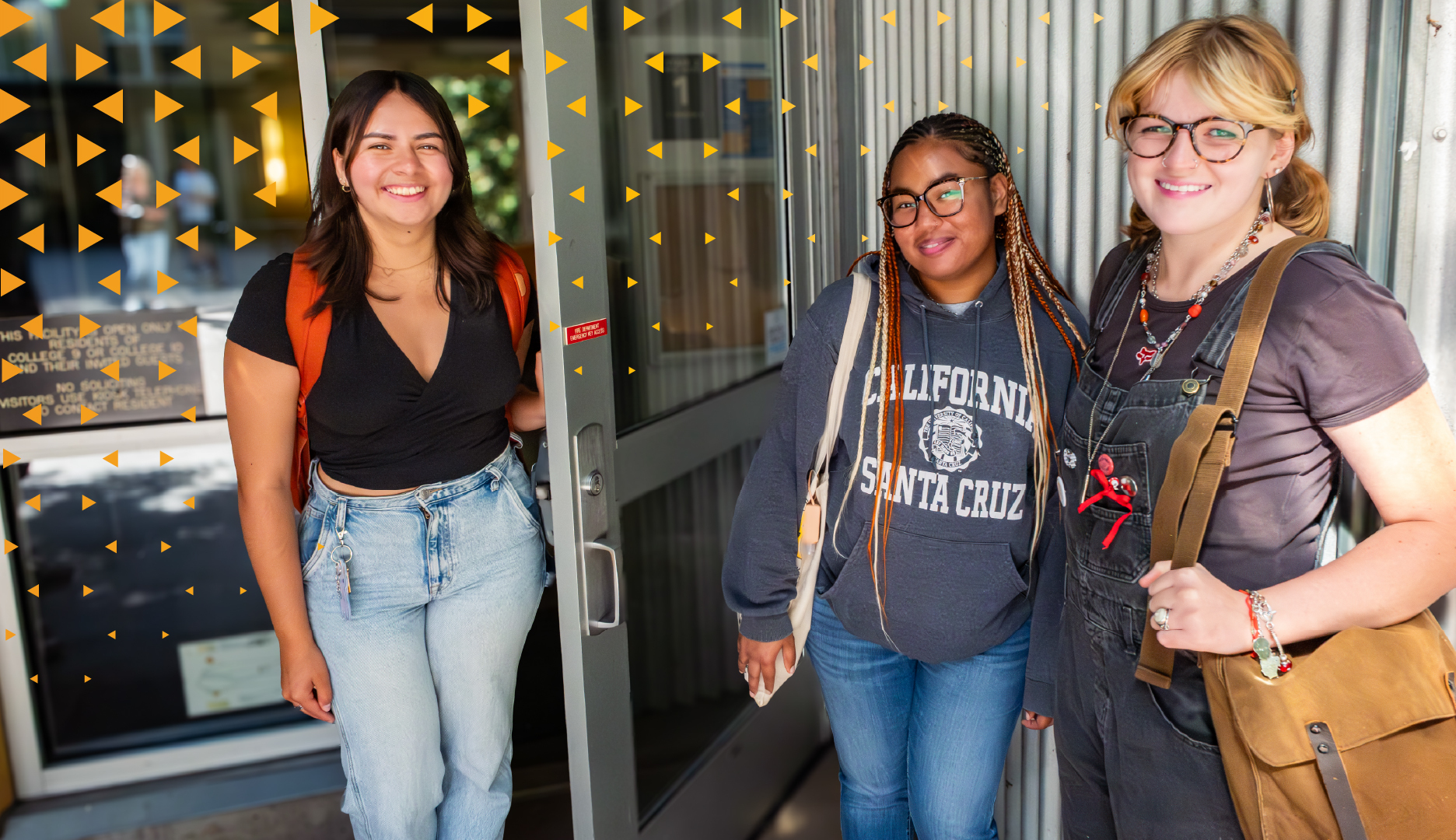Three smiling students at door to residence hall