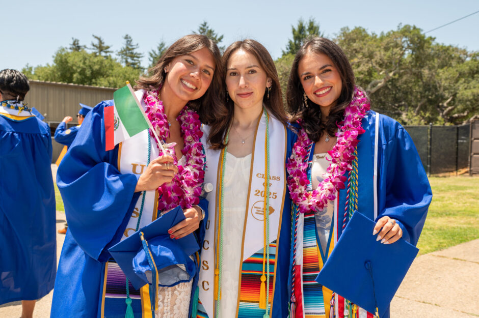 three students in graduation regalia