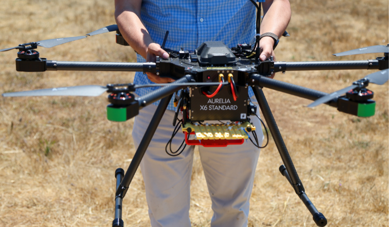 Professor Javier Gonzalez-Rocha holds a drone in a UCSC field