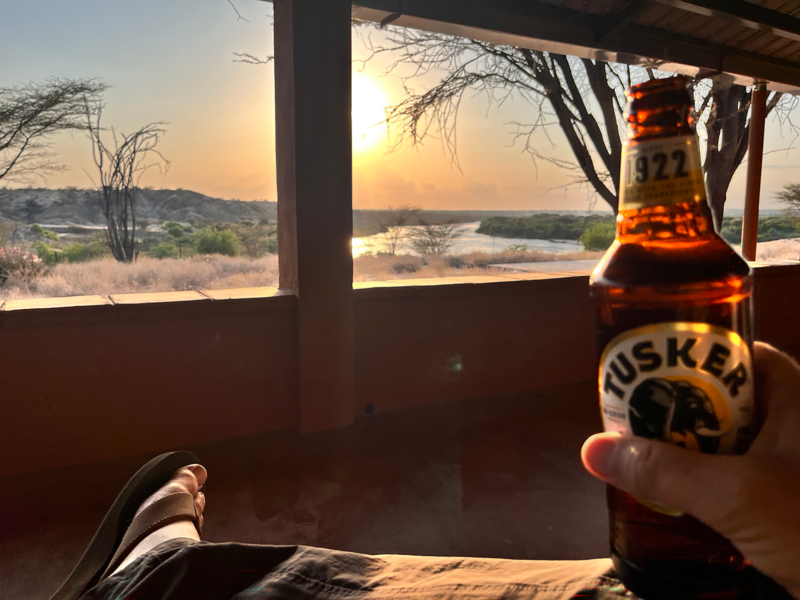 bottle of beer in foreground with Kenyan sunset out window in background