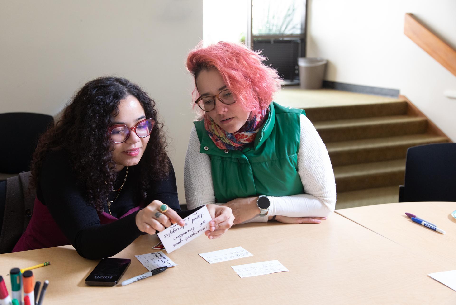 graduate students sitting at a table reviewing notecards together
